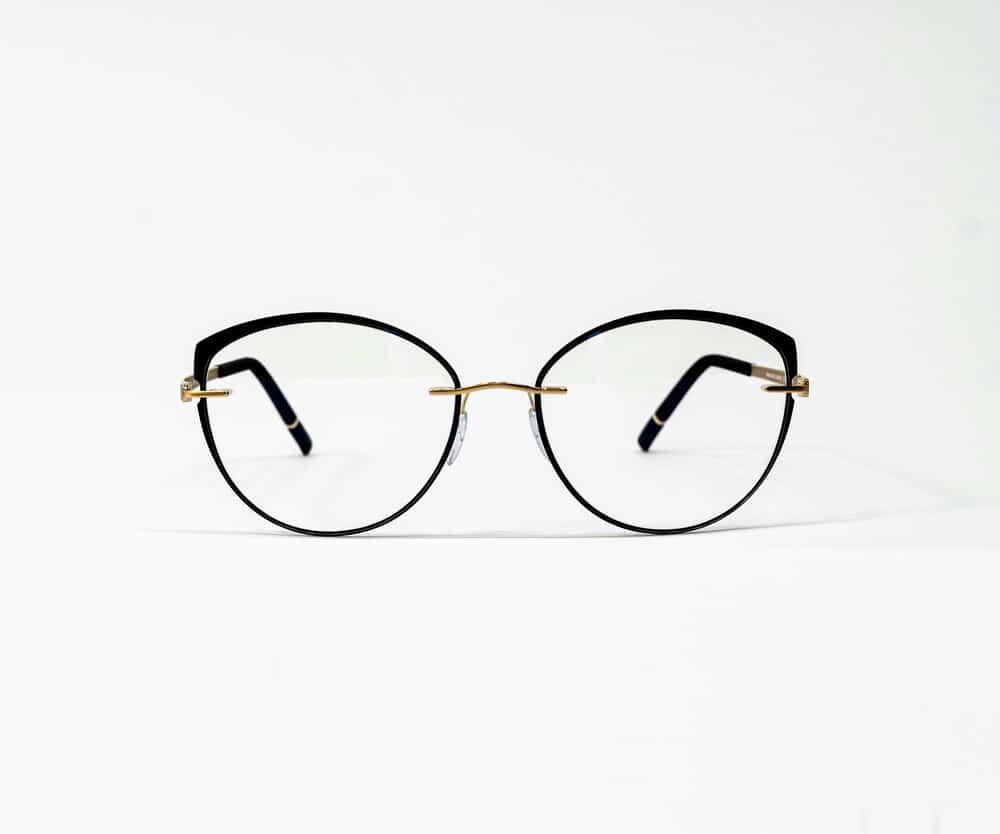 A pristine pair of modern black and gold metal eyeglass frames on a solid white background.