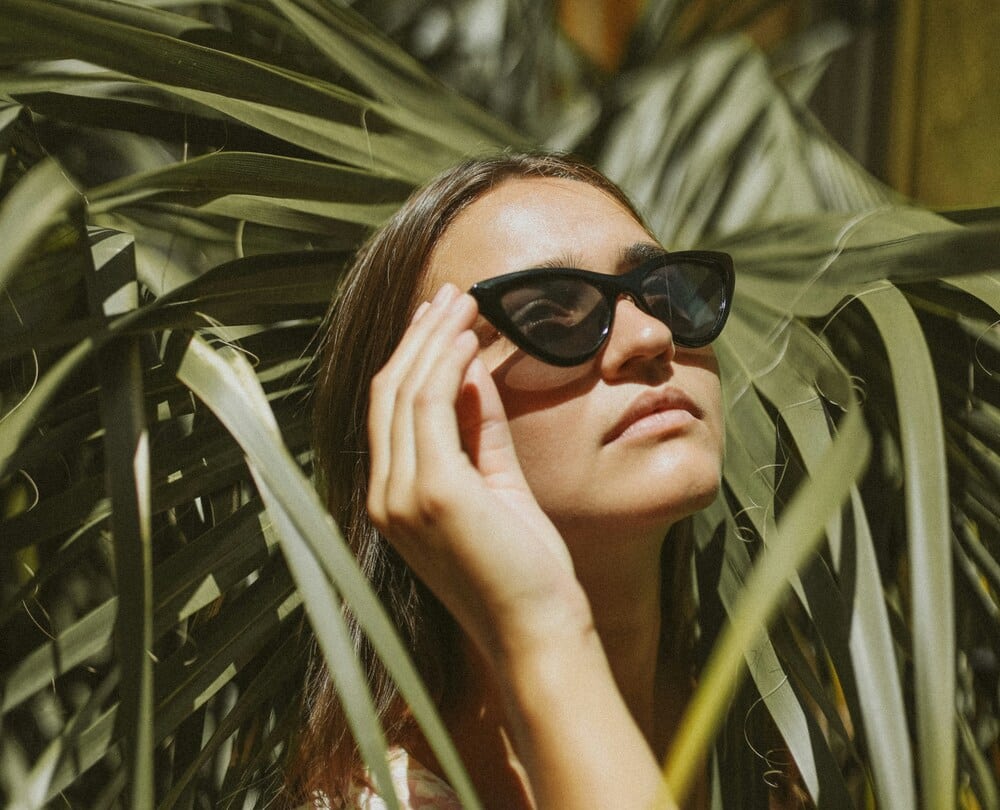 eyewear brand cover 2 woman wearing shades with a palm tree backdrop
