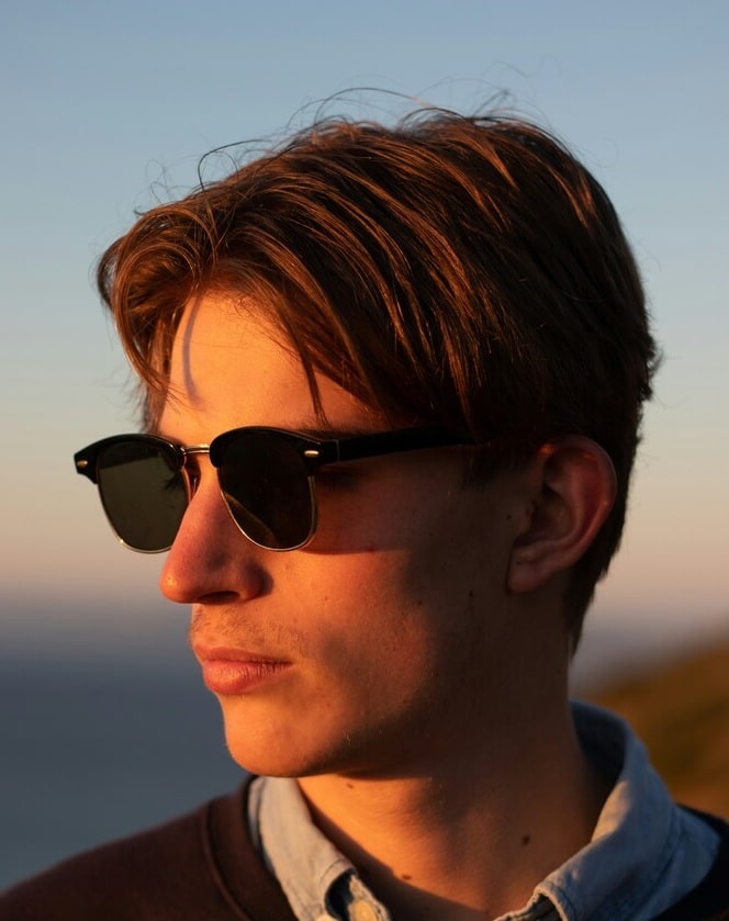 man wearing sunglasses A close-up profile view of a young man wearing black sunglasses during golden hour.